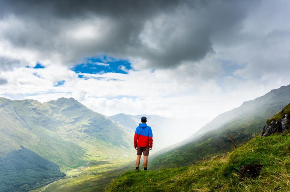 Free Image of Man Standing on Top of Lush Green Hillside 
