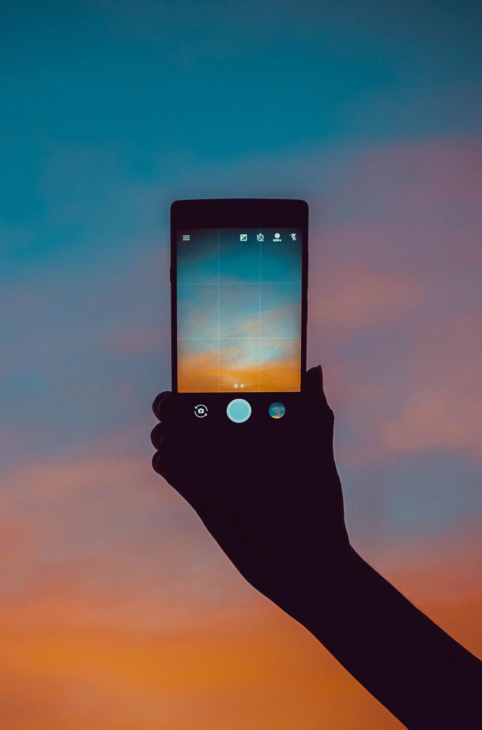 Free Image of Person Holding Cell Phone Up in the Air 