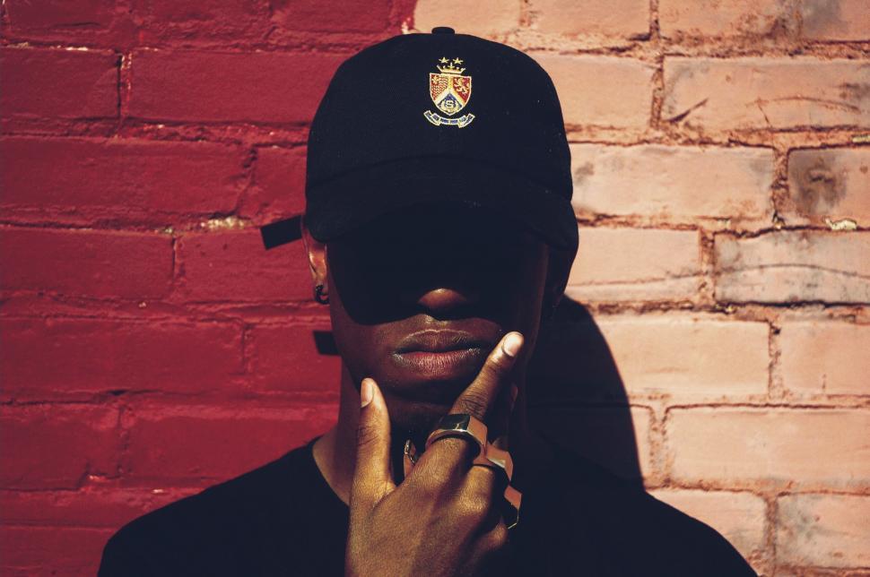 Free Image of Man Wearing Hat Holding Finger Up to Face 