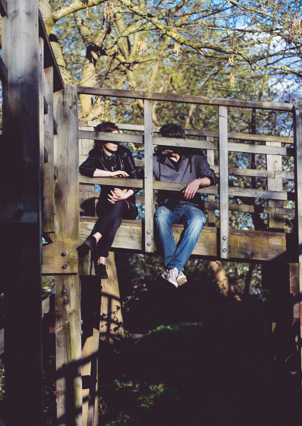 Free Image of Couple Sitting on Top of Wooden Structure 