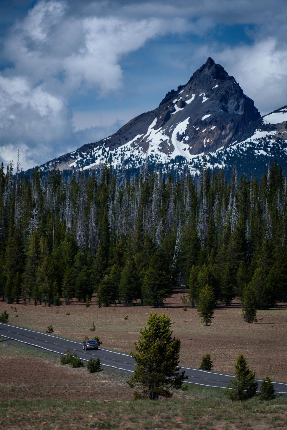 Free Image of Truck Driving Down Road in Front of Mountain 