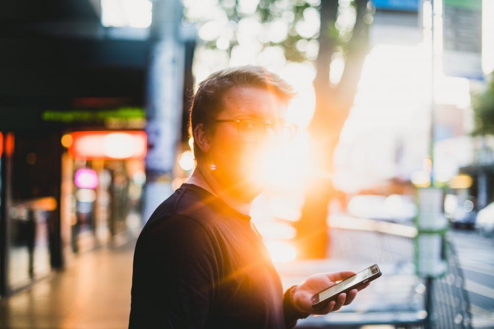 Free Image of Man Standing on Sidewalk Holding Cell Phone 