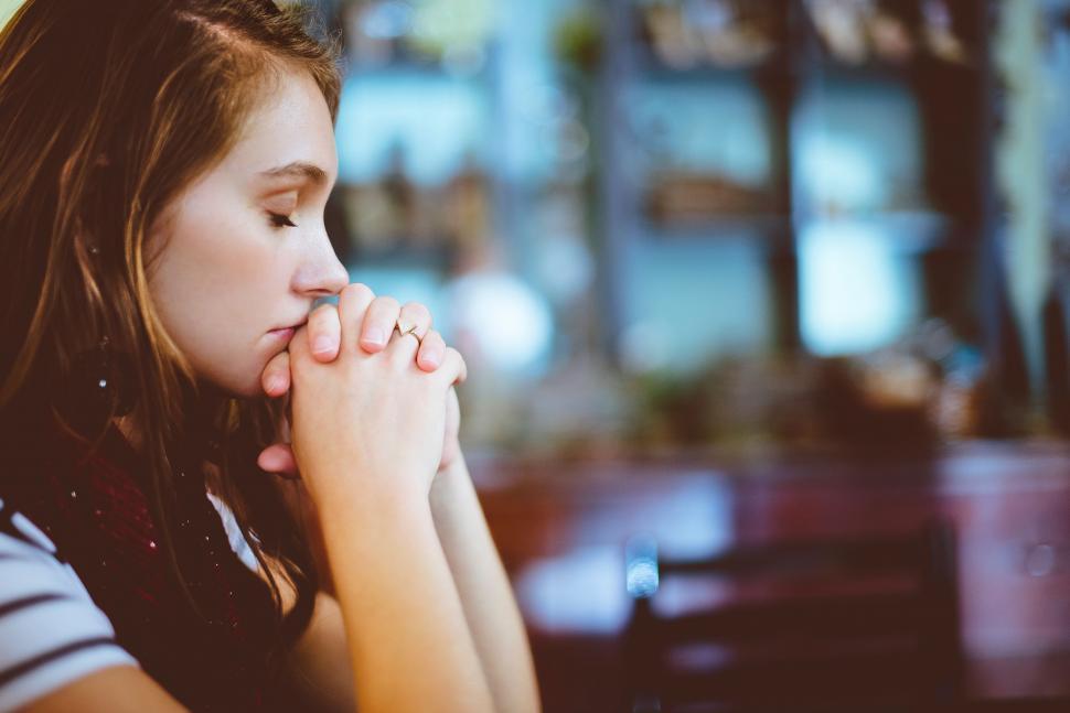 Free Image of Woman Sitting at Table With Hand on Face 