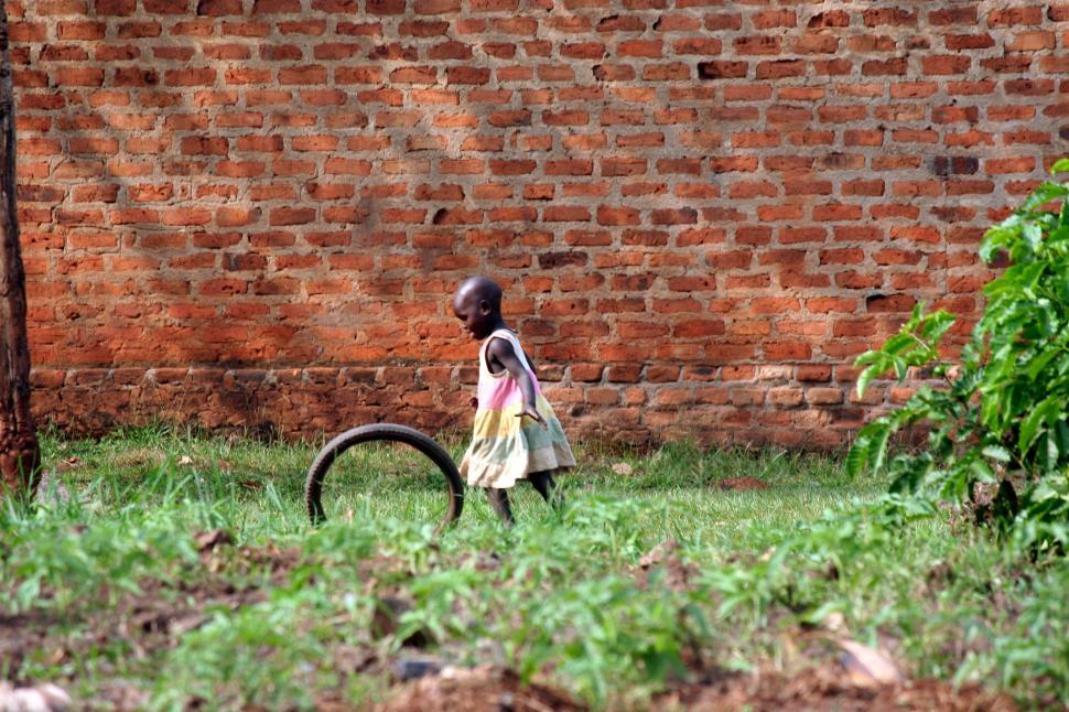 Free Image of Little Girl Standing Next to Tire in Grass 