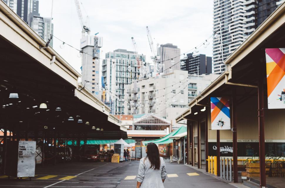 Free Image of Woman Walking Down Street Next to Tall Buildings 