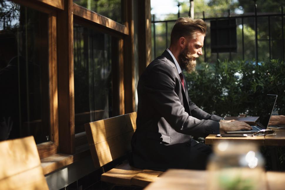 Free Image of Man Sitting at Table Using Laptop Computer 