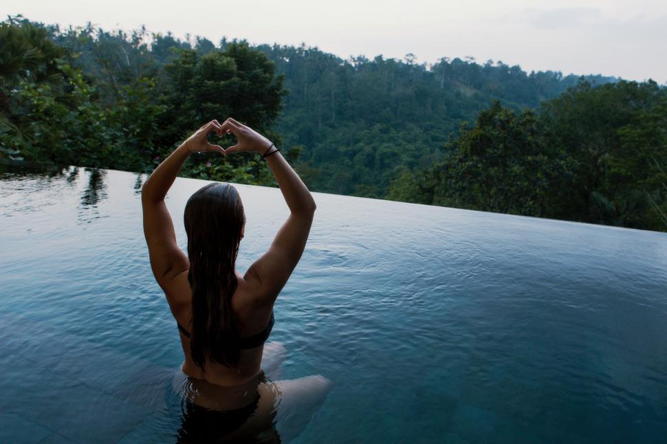 Free Image of Woman Standing in Pool With Hands Raised 