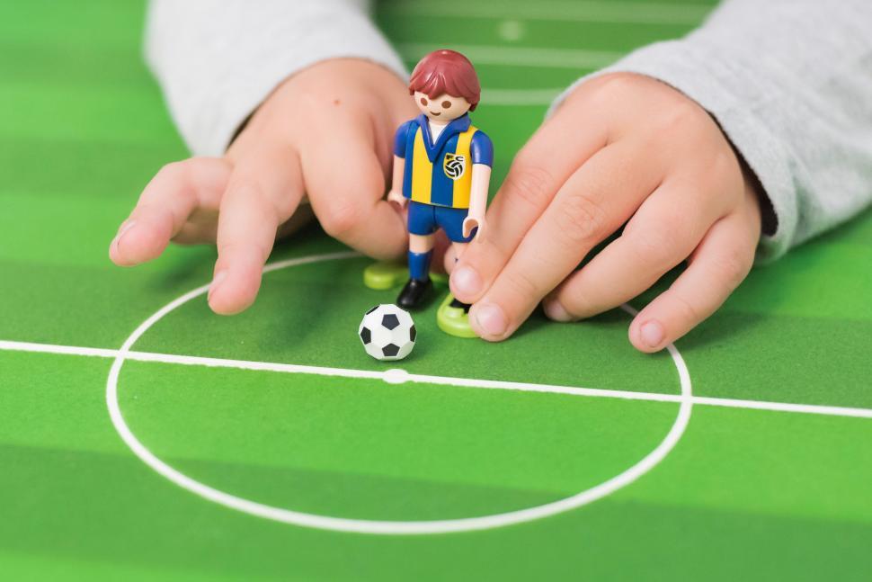 Free Image of Person Holding Toy Soccer Ball on Green Field 