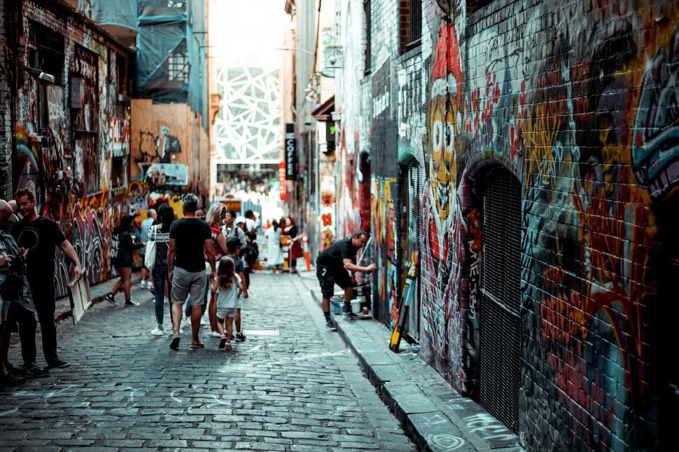 Free Image of Group of People Walking Down Street Next to Tall Buildings 