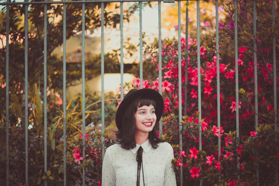 Free Image of Woman Standing in Front of Gate With Flowers 