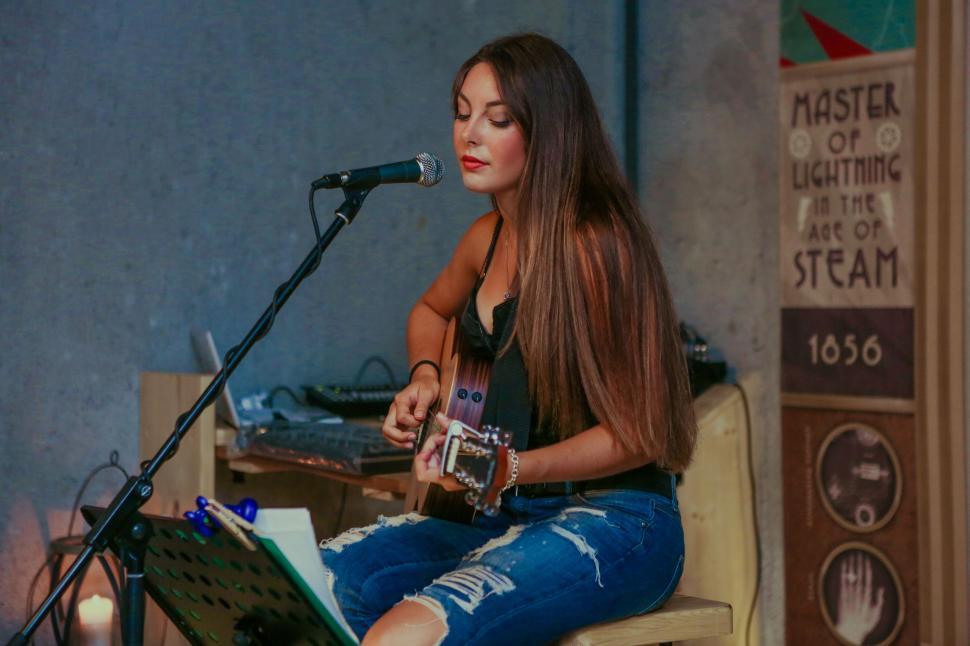 Free Image of Woman Sitting on Chair Playing Guitar 