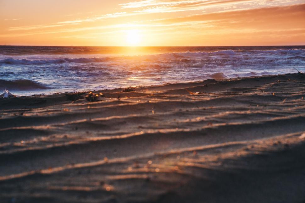 Free Image of Sun Setting Over Ocean on Beach 