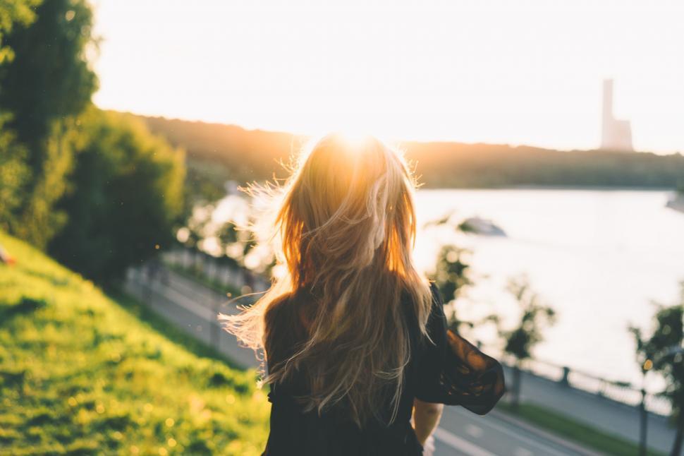 Free Image of Woman Walking Down Hill Towards Body of Water 