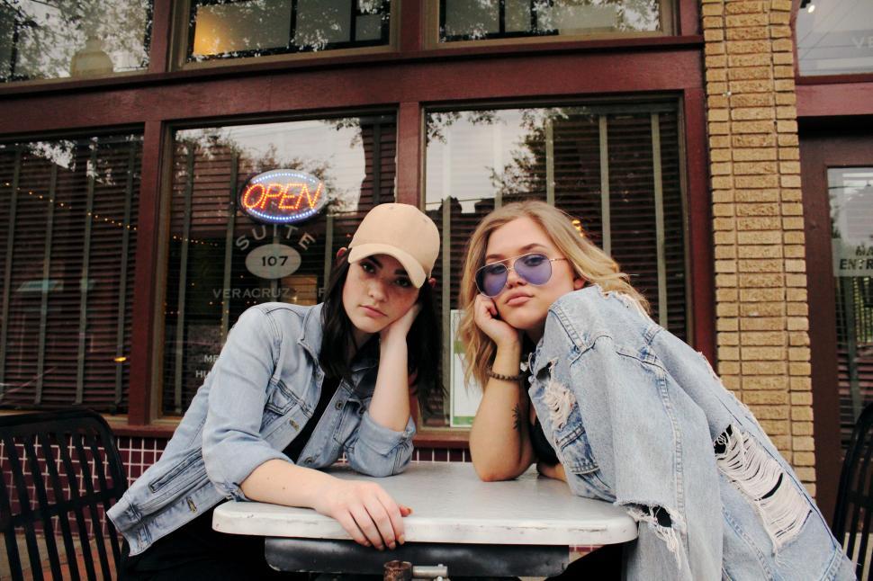 Free Image of Two Young Women Sitting at a Table With Hats On 
