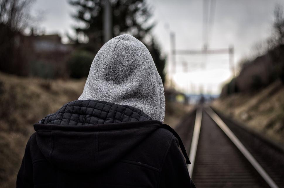 Free Image of Person Wearing Hoodie Walking Down Train Track 