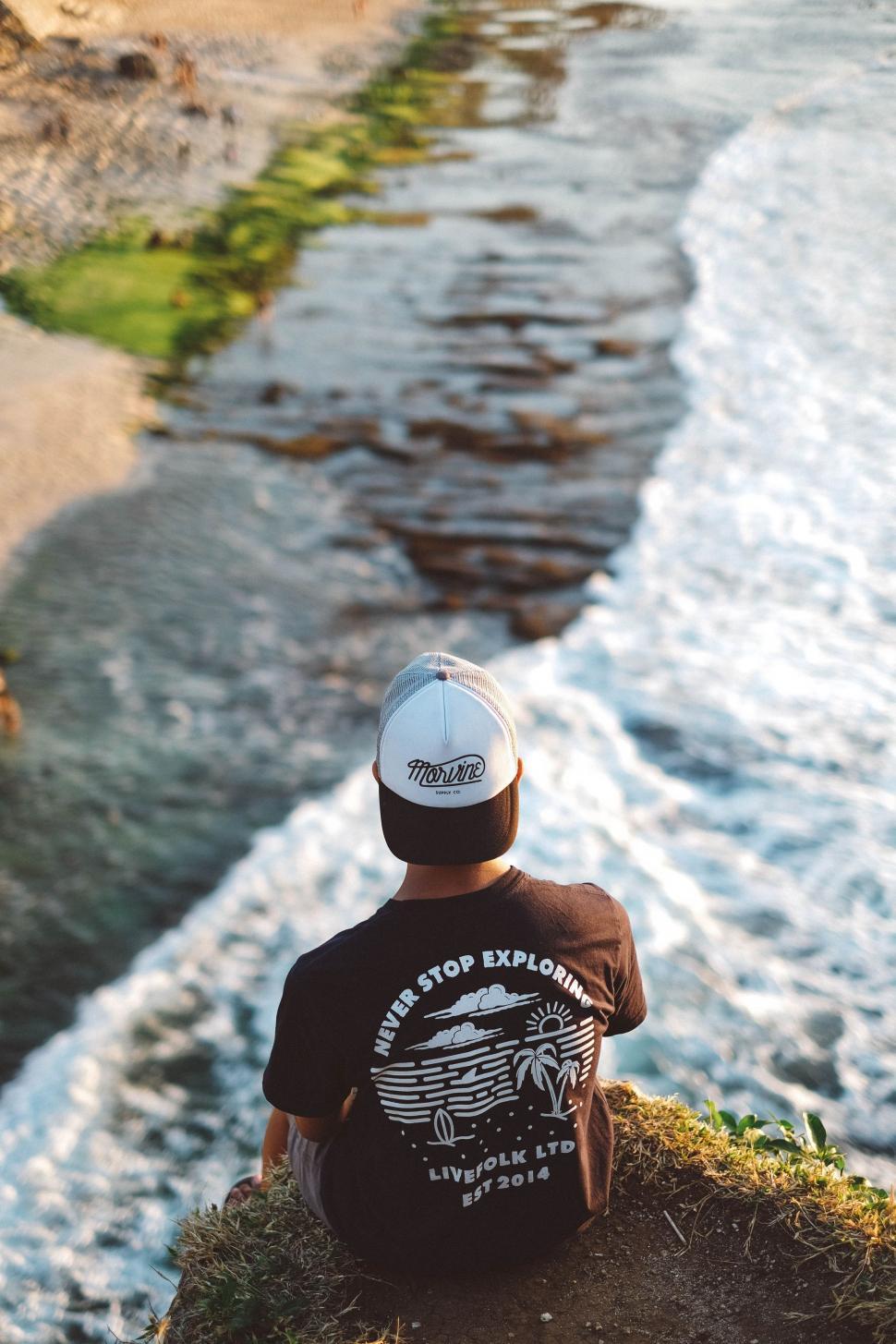Free Image of Person Sitting on Cliff Overlooking Water 