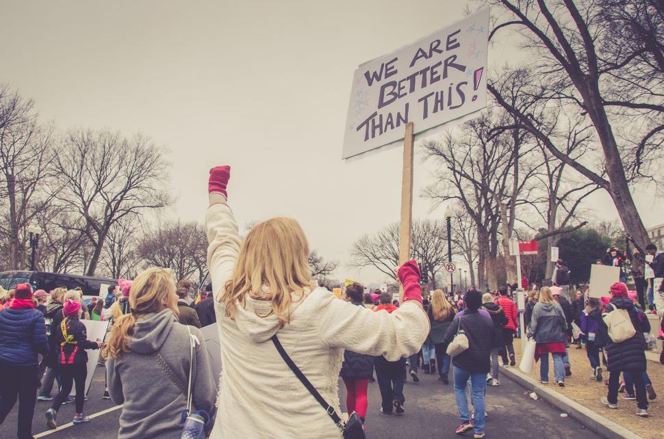 Free Image of Group of People Walking Down a Street Holding Signs 