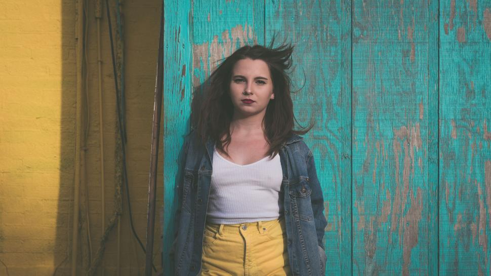 Free Image of Woman Standing in Front of Wooden Wall 