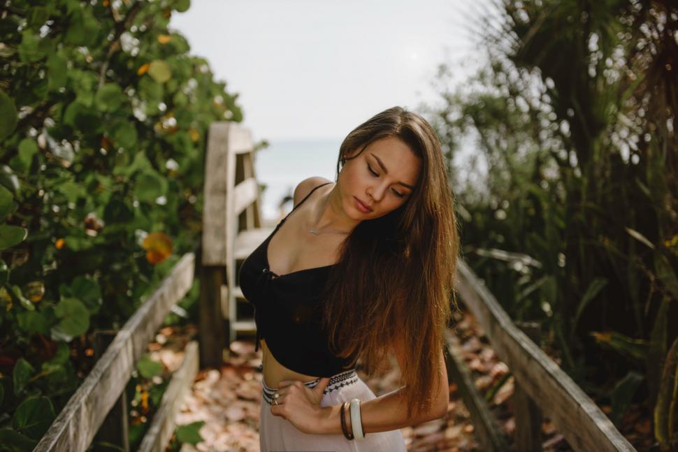 Free Image of Woman With Long Hair Standing on Wooden Bridge 