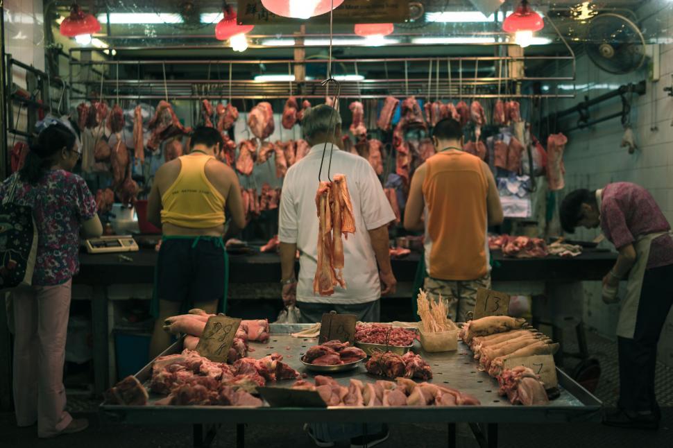 Free Image of Group of People Standing Around a Table Filled With Meat 