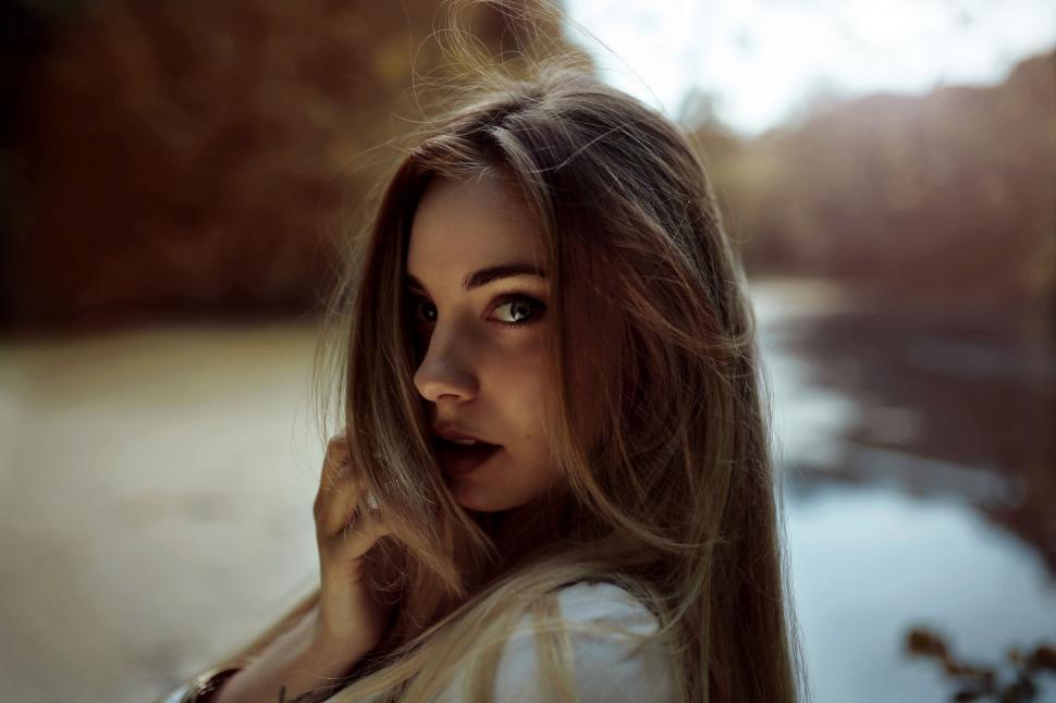 Free Image of Woman With Long Hair Standing by Body of Water 