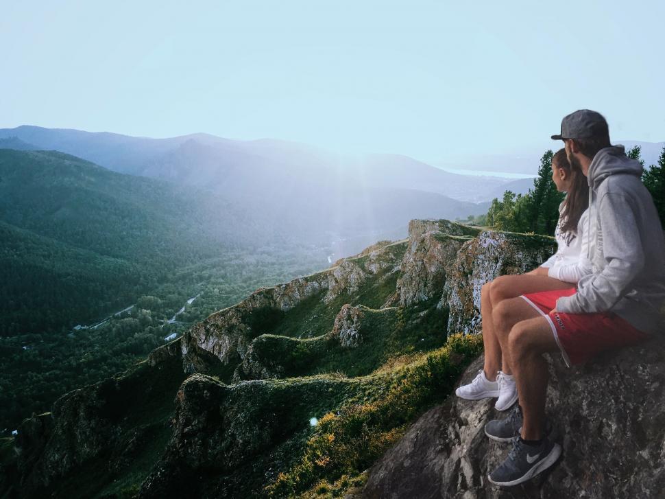 Free Image of Man Sitting on Top of Mountain Talking on Cell Phone 
