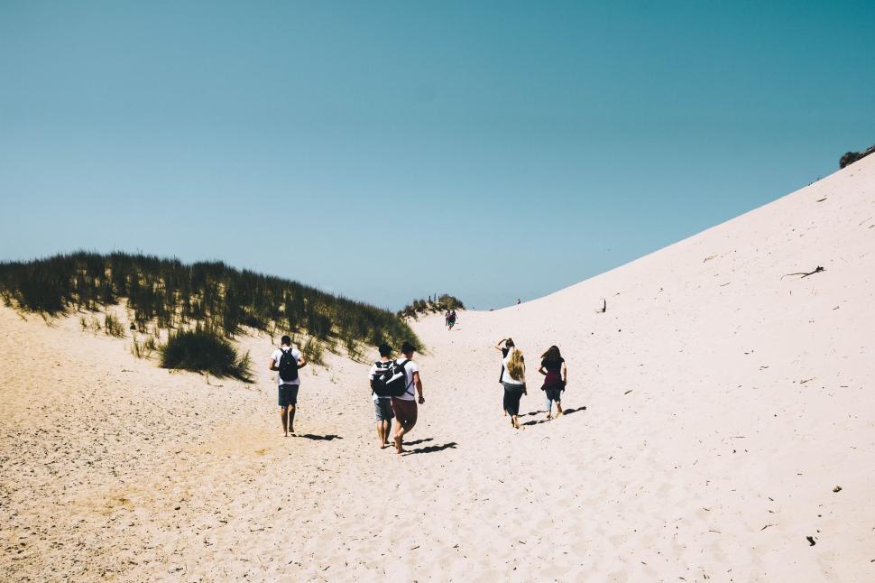 Free Image of Group of People Walking up a Sandy Hill 