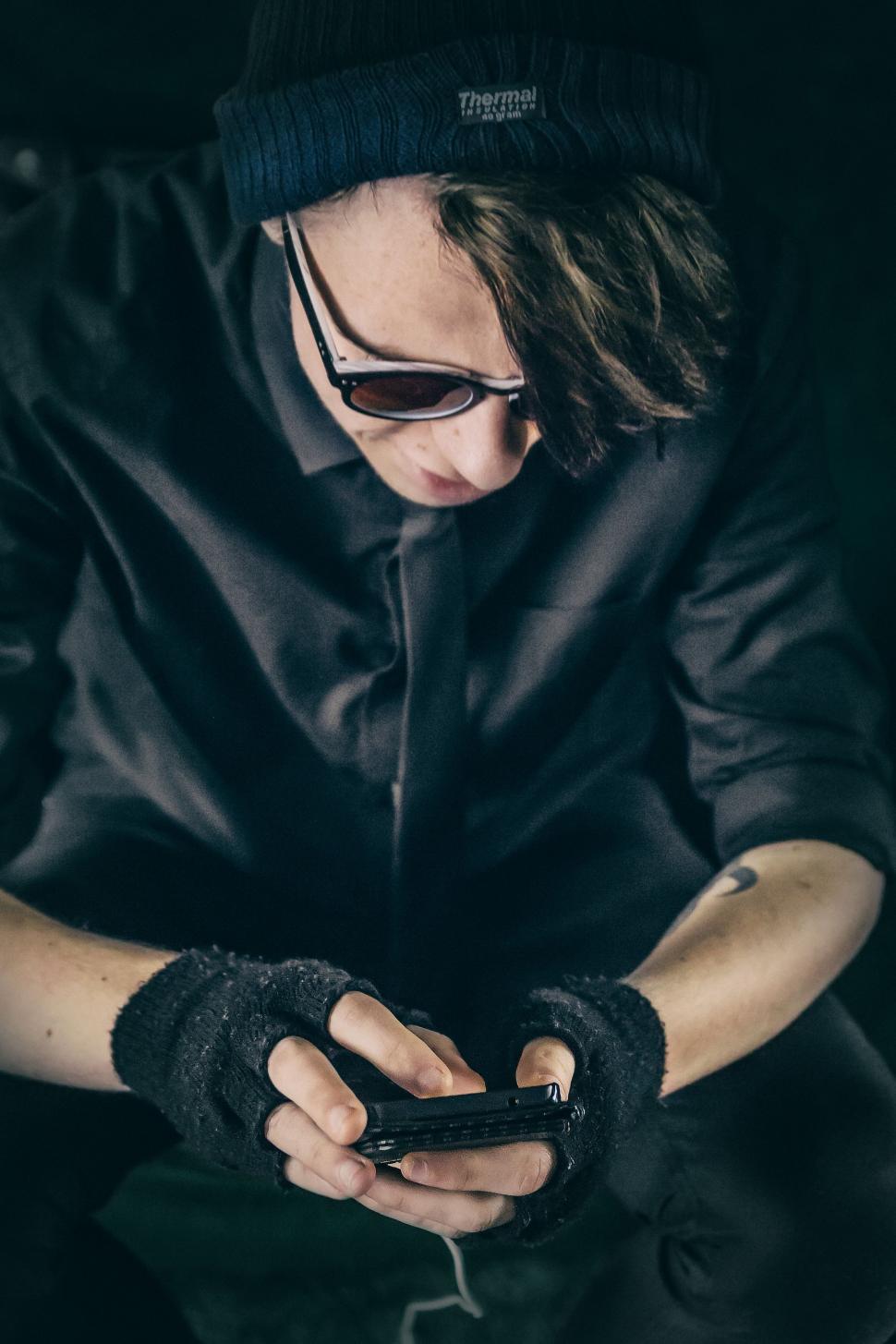 Free Image of Man in Hat and Sunglasses Looking at Cell Phone 