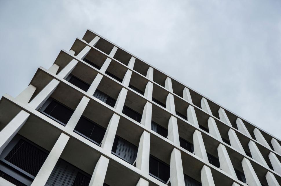 Free Image of Tall Building With Numerous Windows Against Cloudy Sky 