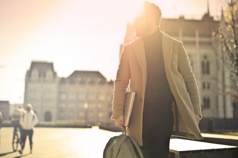 Free Image of Young adult bearded male backlit by the sun, walks on street wit 