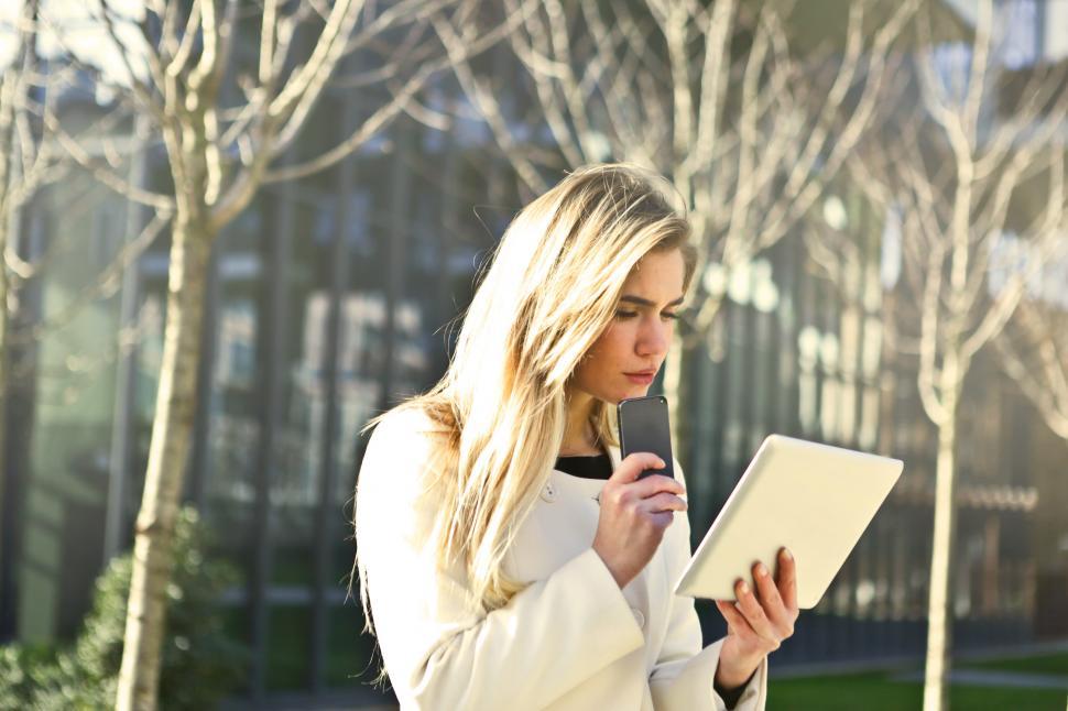 Free Image of Young Woman In White Jacket Using Smartphone And Tablet 