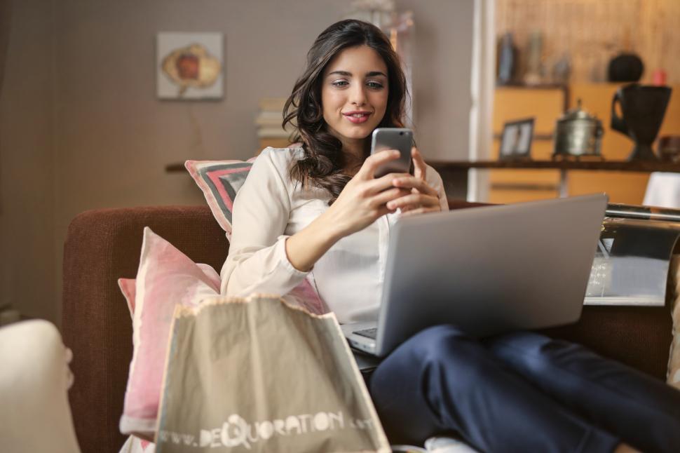 Free Image of A young woman looking at her mobile phone while working on her l 