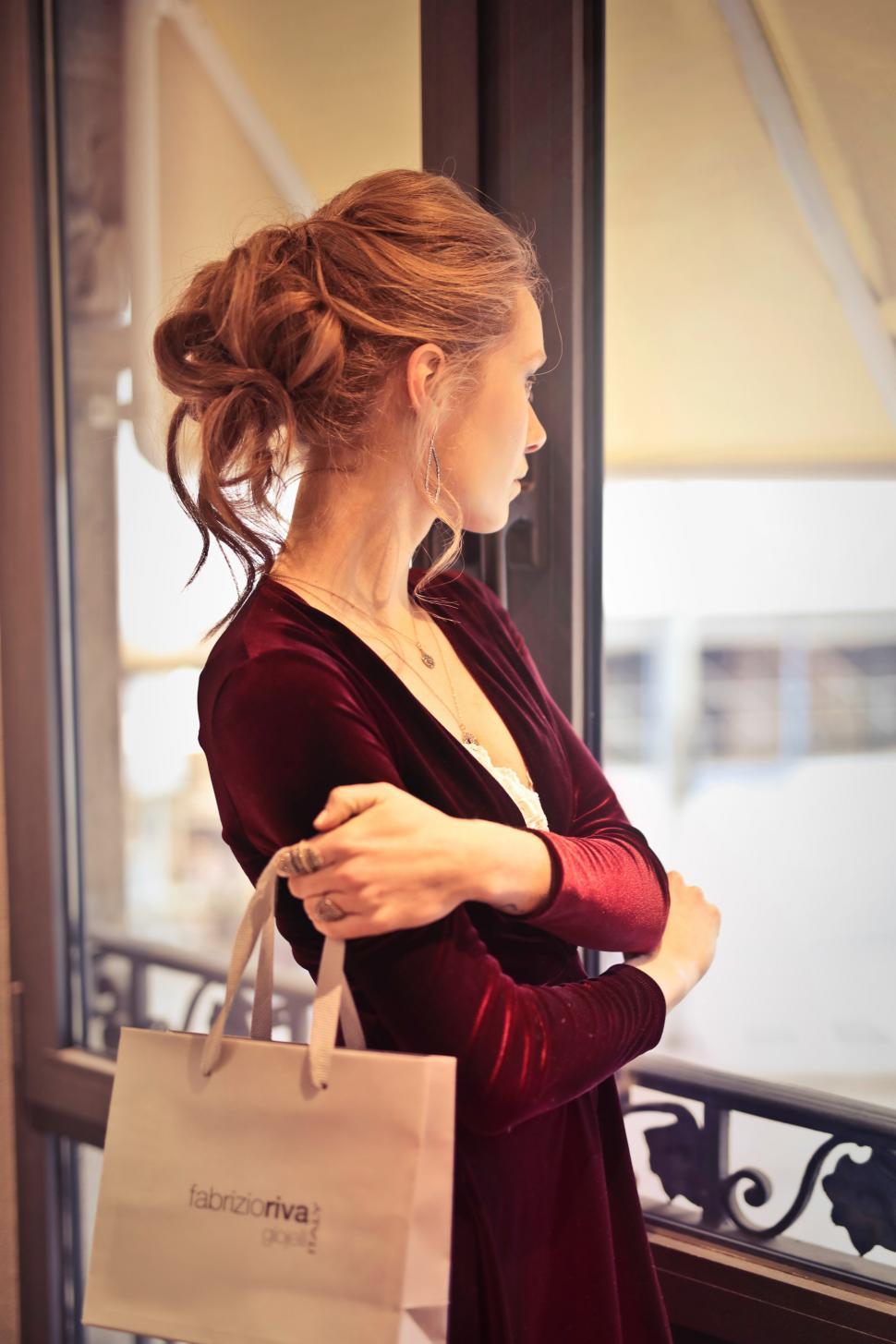 Free Stock Photo of A young blond woman with elegant hair bun holding a shopping  bag