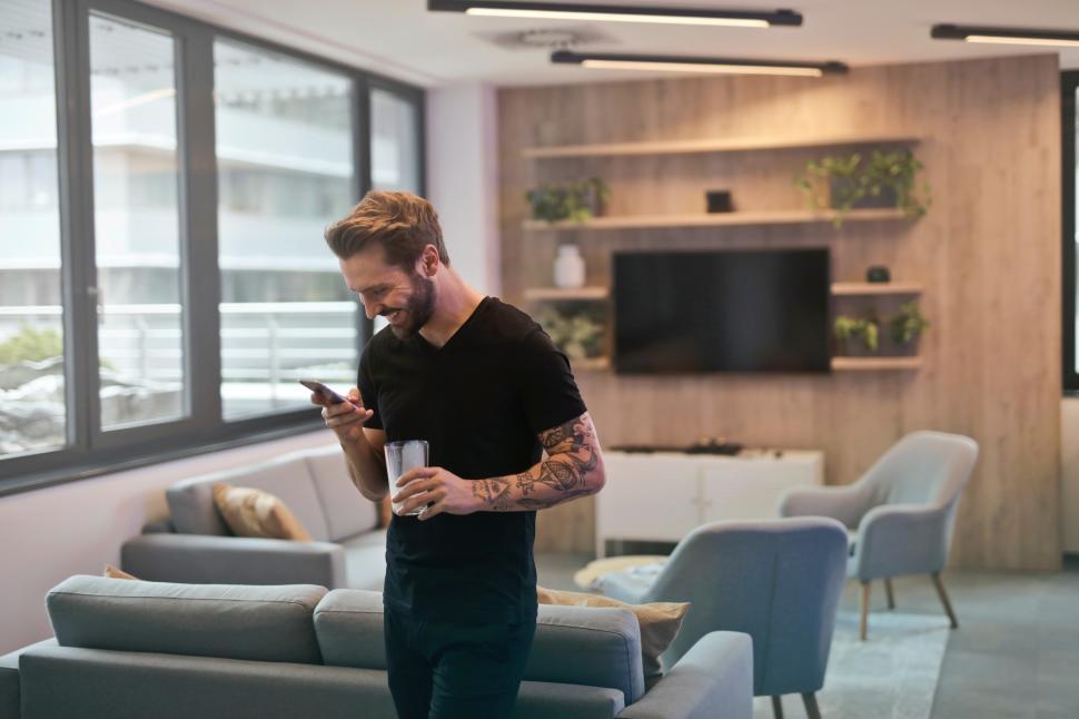 Free Image of A young caucasian man looking at his mobile phone in the living 