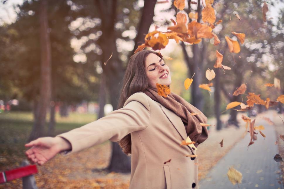 Free Image of Beautiful young adult woman wearing brown scarf playing among fa 