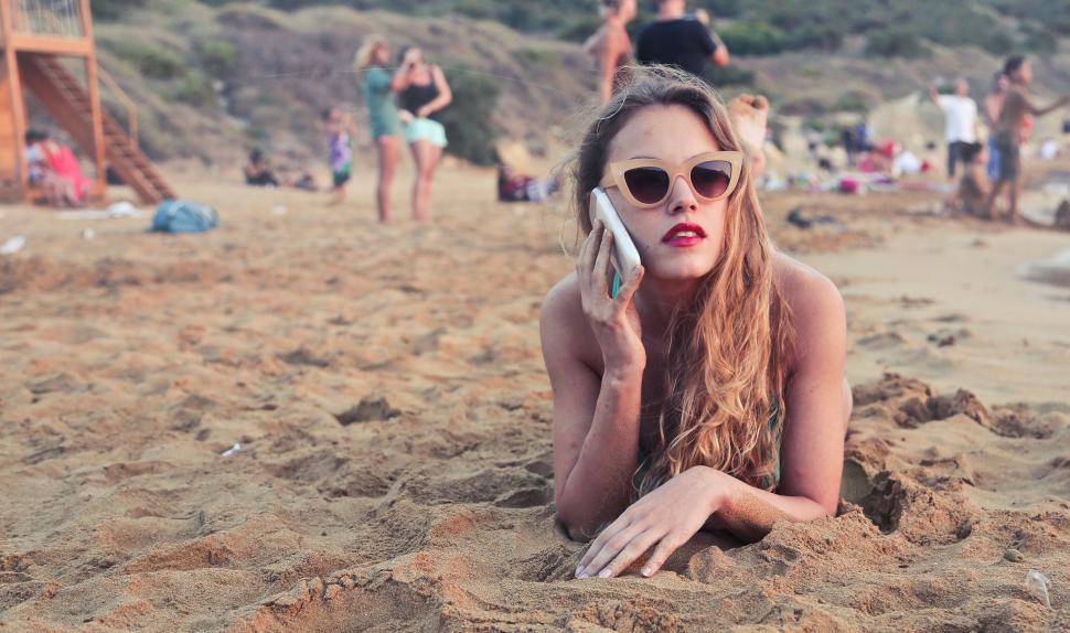 Free Image of A young blonde woman calling on her mobile phone in the sand 