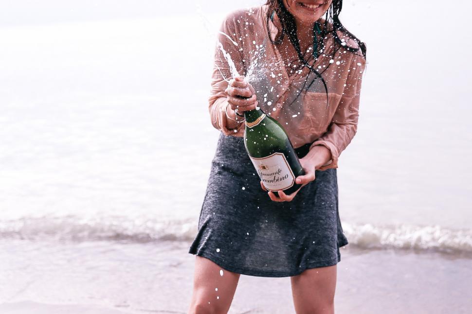 Free Image of A young caucasian woman splashing champagne on the beach 