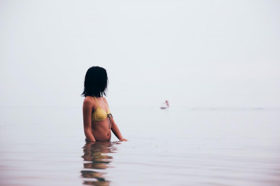 Free Image of A young woman in bikini standing in still water 