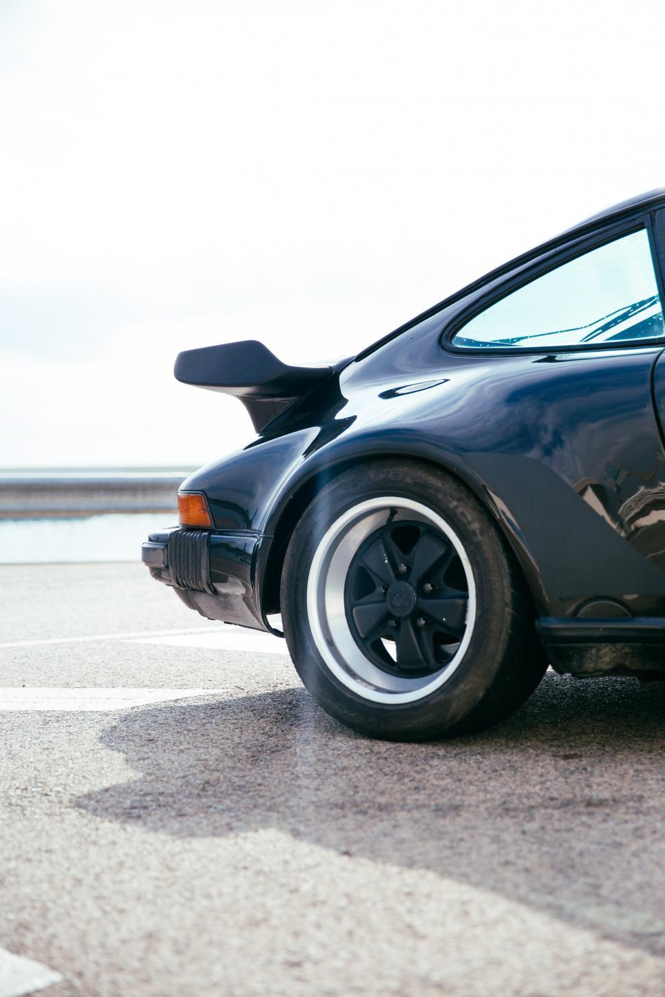 Free Stock Photo of Side view of a black sports car rear wheel and spoiler