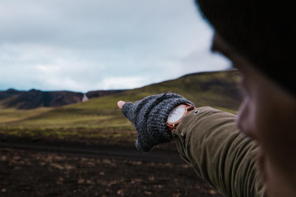Free Image of A young Caucasian man pointing toward mountains 