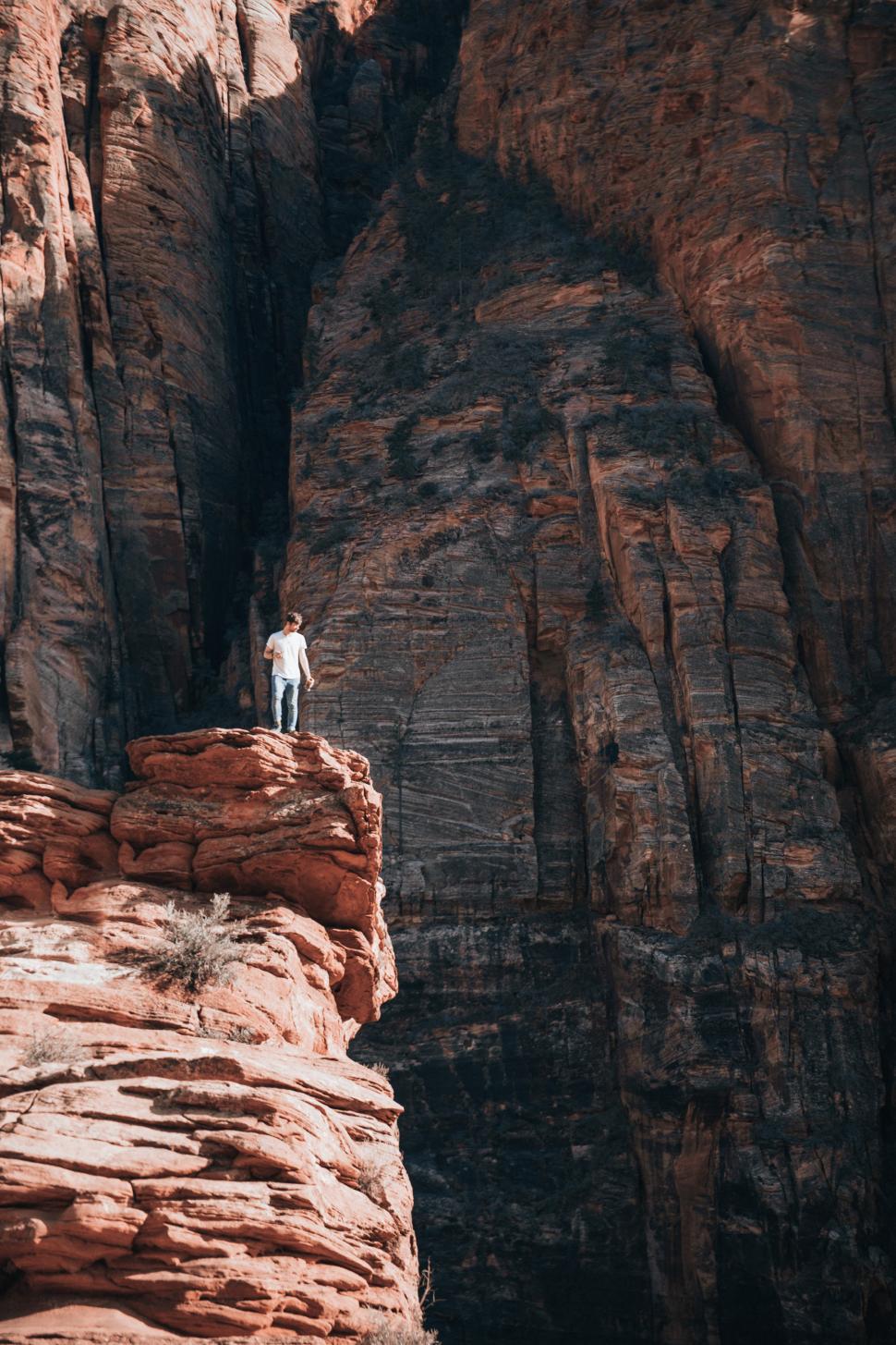 Free Image of A young caucasian man standing on a layered rock 