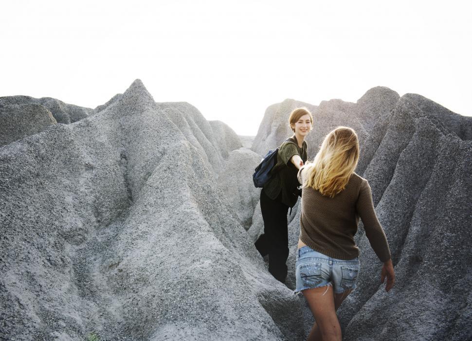 Free Image of A young caucasian woman holding hand of another during a hike 