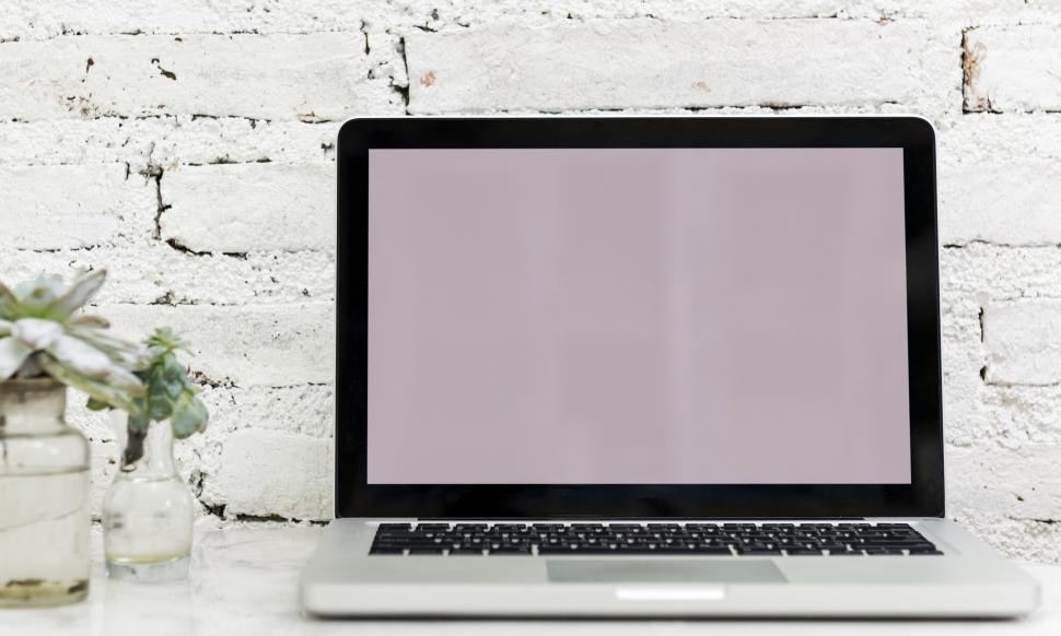 Free Image of A laptop along with glass flower pots the table 