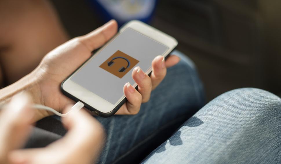 Close up a mobile phone in a hand being charged by connecting a