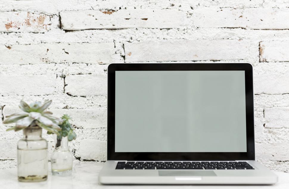 Free Image of A laptop along with glass flower pots the table 