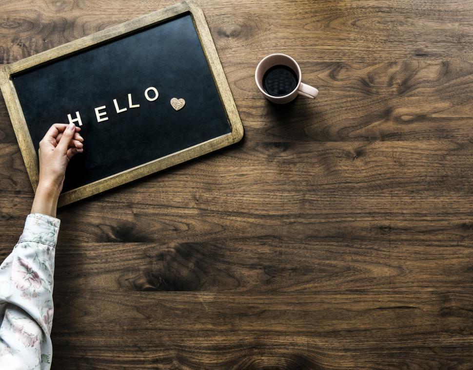 Free Image of Flat lay of a hand arranging the text HELLO on a slate blackboar 