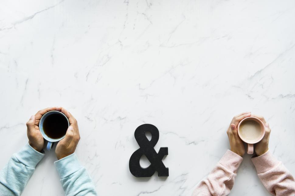 Free Image of Flat lay of coffee mugs held in the palms of two hands 