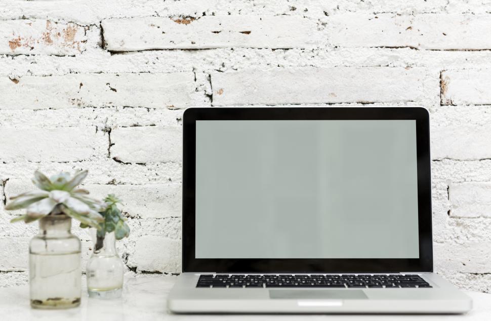 Free Image of A laptop along with glass flower pots the table 