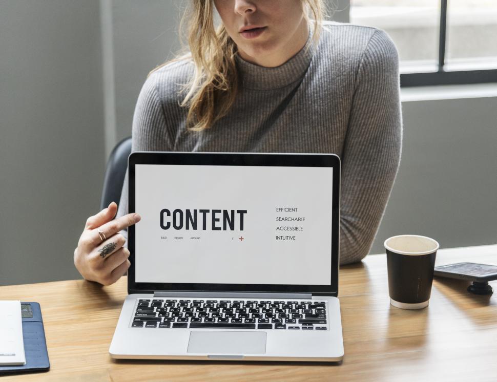 Free Image of A young Caucasian woman pointing finger at a laptop 