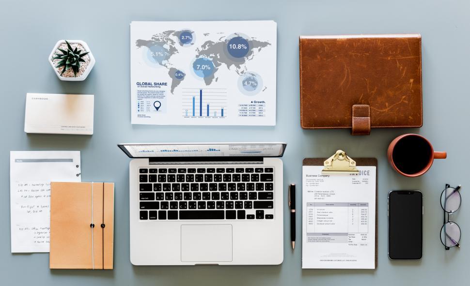 Free Image of World map graphic with laptop and a coffee mug along with other items  